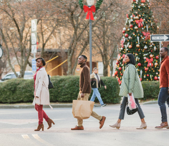 Two Couples walking across River Street downtown with shopping bags and a Christmas tree in the background